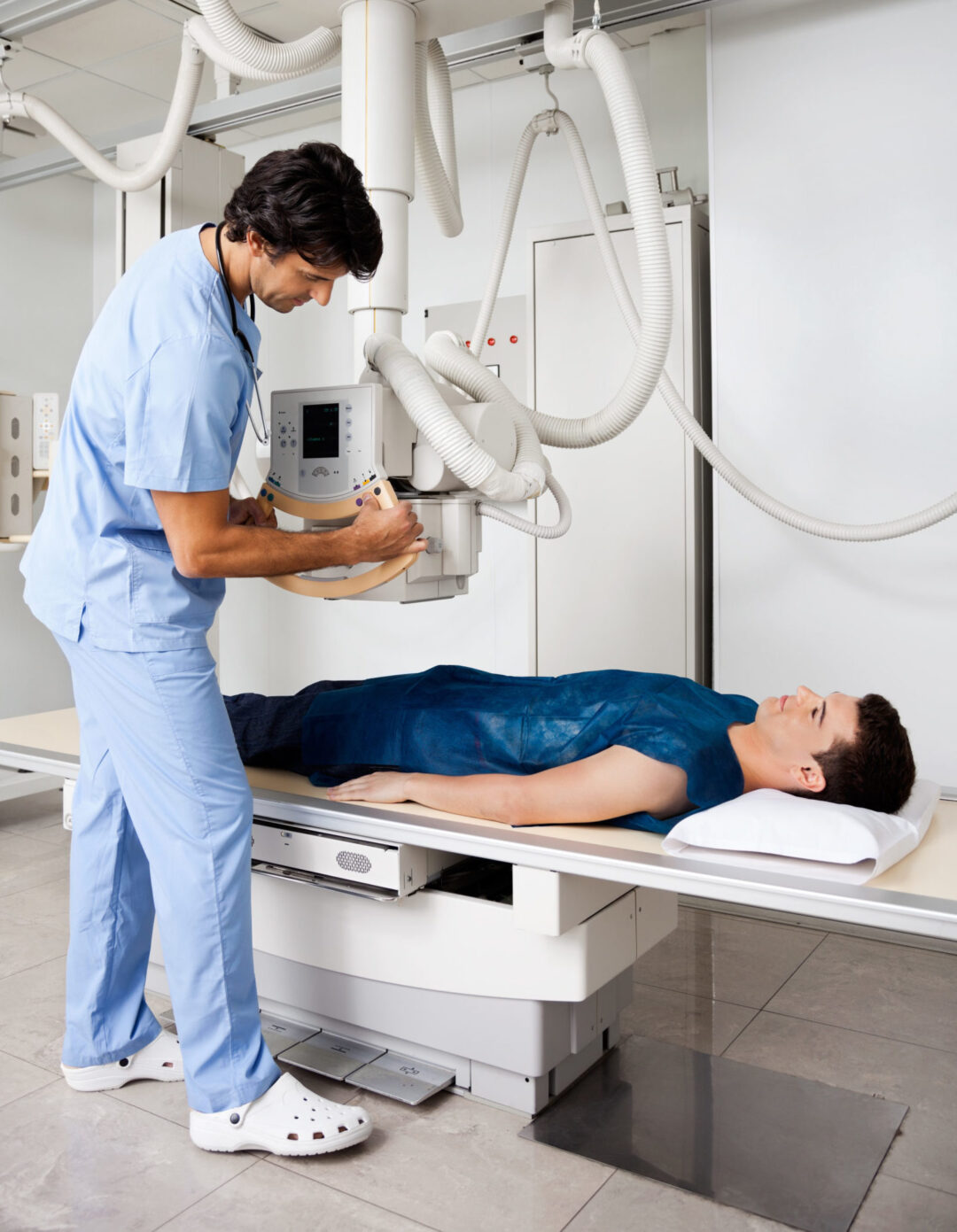 Doctor using medical imaging on male patient lying on table